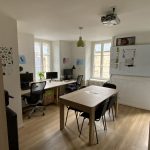 Espace partagé lumineux avec trois postes de travail et une table de réunion